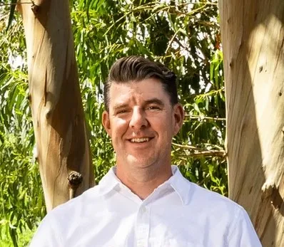 Jon Sitlington, founder of Hawk IT Solutions, smiling in a white shirt outdoors
