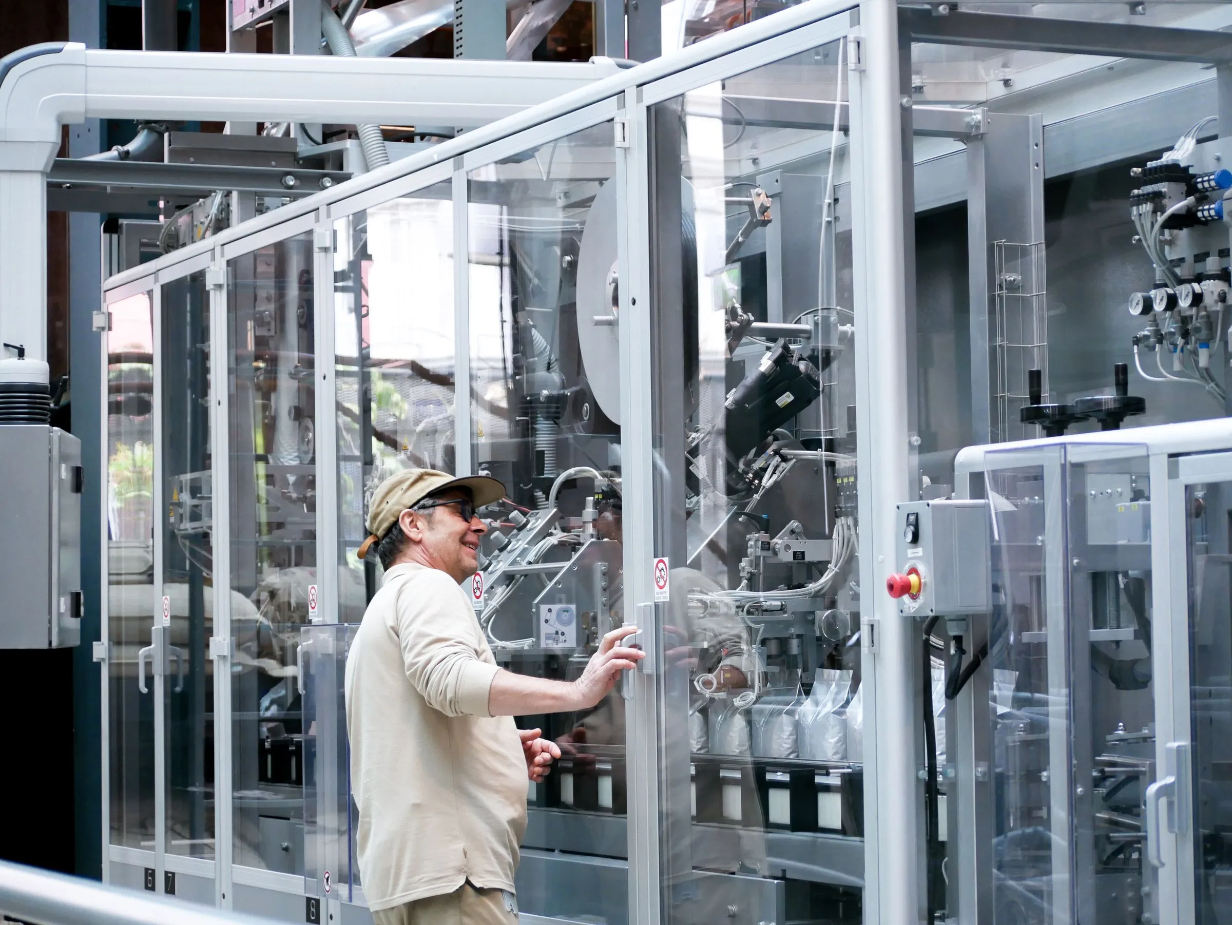 Operator checking an enclosed automated packaging line on a production floor