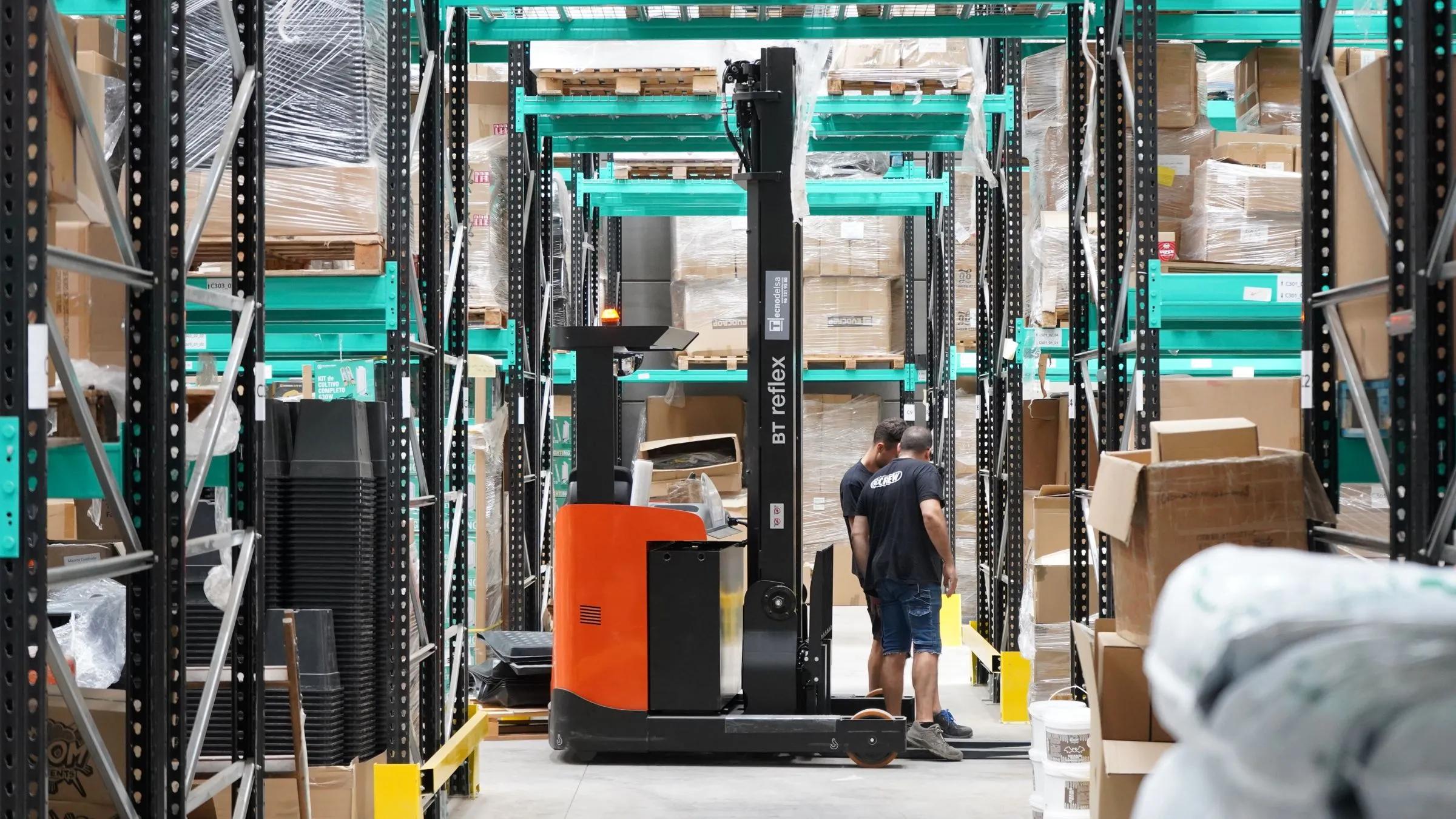 Warehouse aisle with tall pallet racking and a reach truck